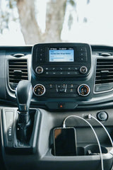 RV rental interior: Dashboard with Diplo's "Heartless" playing on the infotainment system and a phone charging.