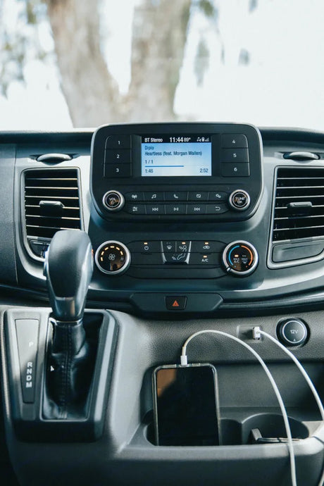 RV rental interior: Dashboard with Diplo's "Heartless" playing on the infotainment system and a phone charging.
