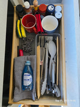 Compact RV rental kitchen drawer featuring essential spices, dish soap, sponges, and cooking tools for travelers.