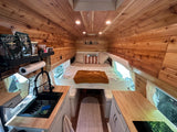 Stylish wood-paneled van conversion rv rental interior with cozy bed, kitchen area, and ambient lights. Perfect for road trips.
