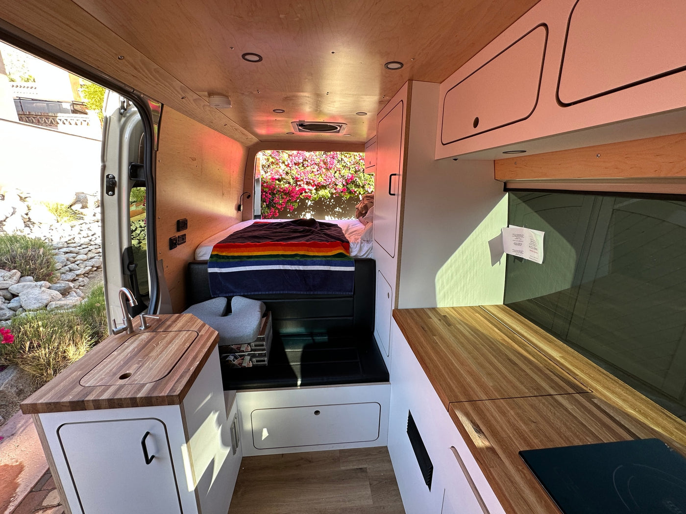 Cozy RV rental interior with a functional kitchen, comfortable bed, and custom wood finishes, ideal for travel. — photo 2
