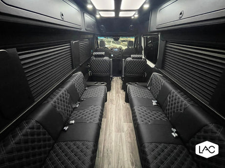 Luxury custom RV rental interior: spacious cabin with quilted leather lounge seating & wood-like floor.