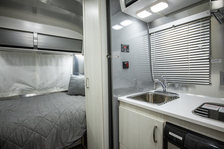  featuring stainless steel appliances and dark seating.|RV rental interior: A compact kitchen with sink — photo 2