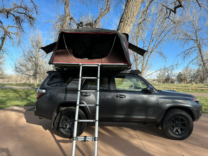  and ladder. Two chairs & fire pit are ready. Great for RV rental style adventures.|Adventure-ready grey SUV with rooftop tent & ladder setup. A unique RV rental alternative for camping trips.|Custom RV rental: Dark gray Toyota 4Runner with iKamper rooftop tent — photo 5
