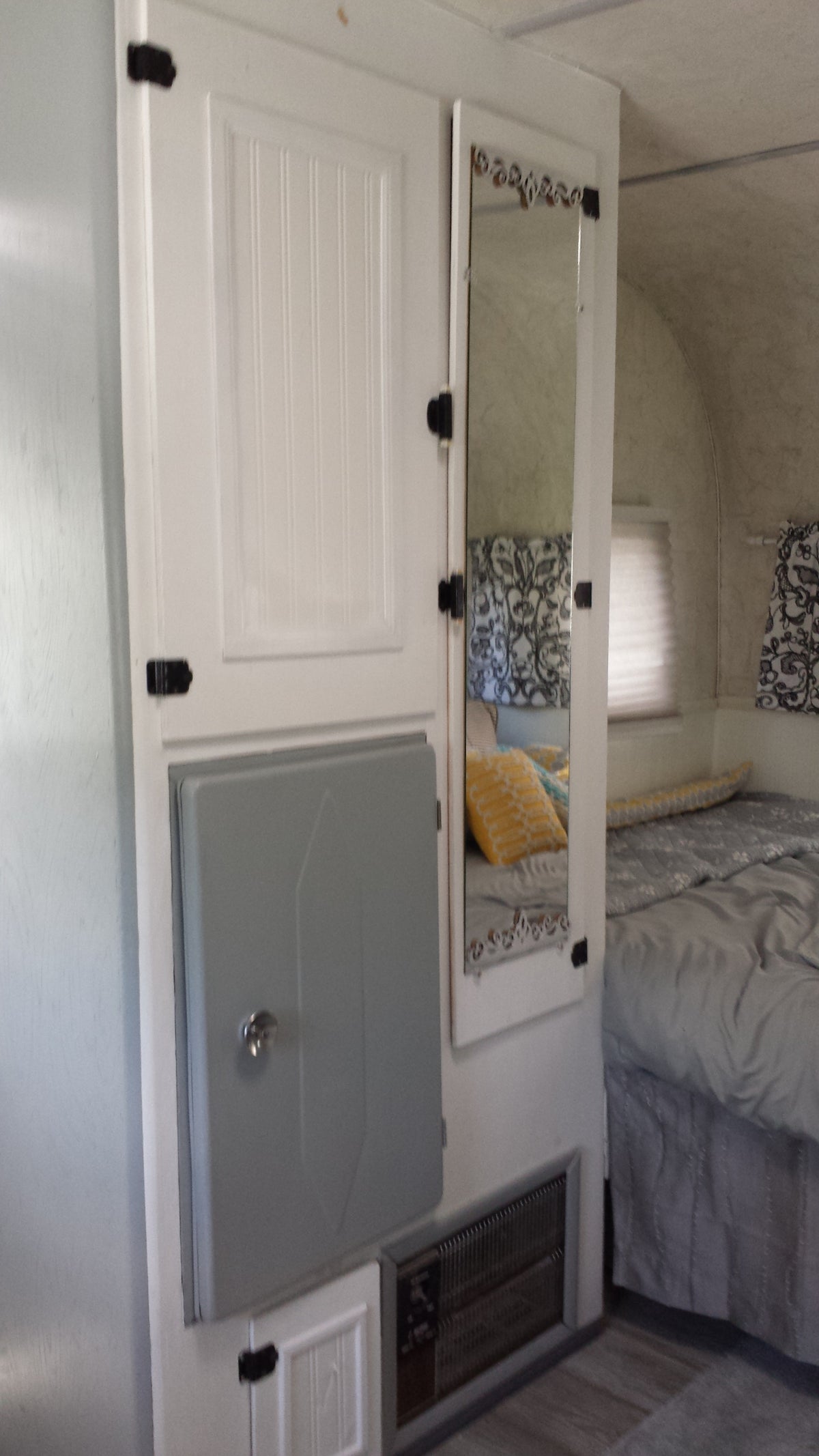 Inside a cozy RV rental: white storage cabinet, integrated mirror showing the bed, and a lower utility panel for convenience. — photo 2