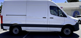 A clean white cargo van, often chosen for RV rental conversions, parked on asphalt.