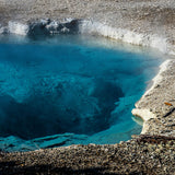 Experience clear blue geothermal pools on your RV rental adventure. This vibrant hot spring reveals its rocky bottom. Steam rises.