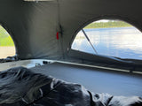 Cozy RV rental pop-top offers a beautiful lake view from bed. Perfect for nature-filled camping adventures.