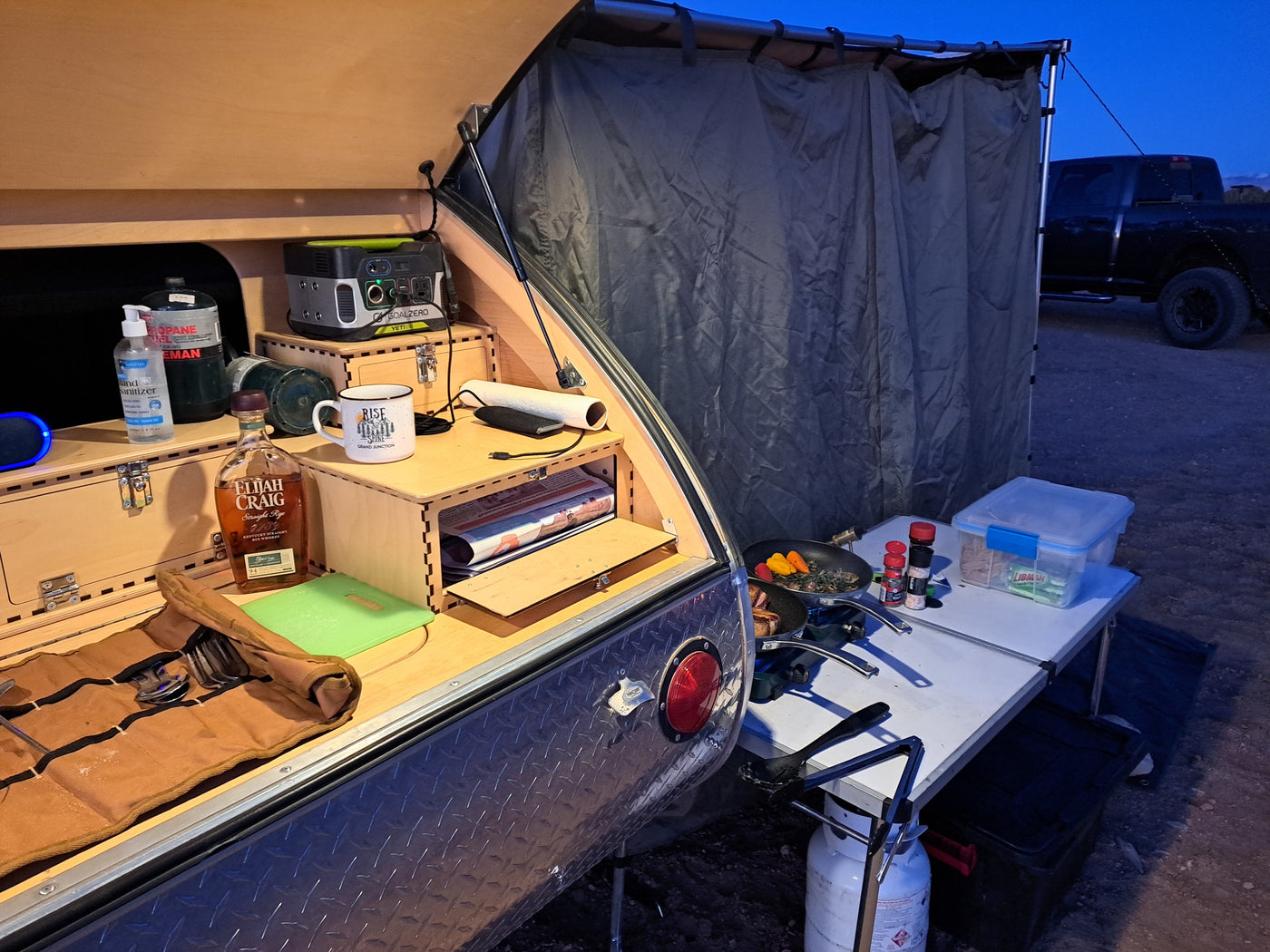 RV rental: Teardrop trailer's outdoor kitchen, equipped with cooking stove, power station, and camping gear for a wilderness meal. — photo 7