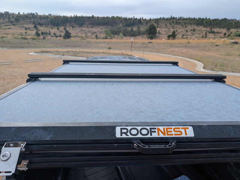  showing water droplets and crossbars in a scenic landscape.|Black pickup truck with a rooftop tent and fuel cans — photo 7