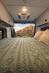 Cozy RV rental bedroom with a stunning mountain landscape view, offering a perfect escape for nature and van life adventures.