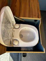 Compact RV rental toilet setup with open lid, showing its design and integrated storage.