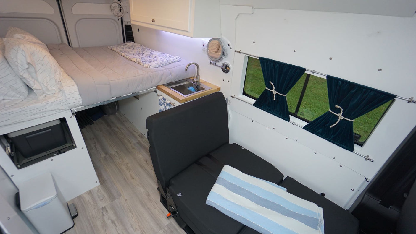 Explore this modern rv rental camper van interior with a comfortable bed, compact kitchen, and versatile seating.