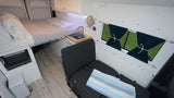 Explore this modern rv rental camper van interior with a comfortable bed, compact kitchen, and versatile seating.