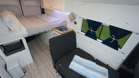 Explore this modern rv rental camper van interior with a comfortable bed, compact kitchen, and versatile seating.