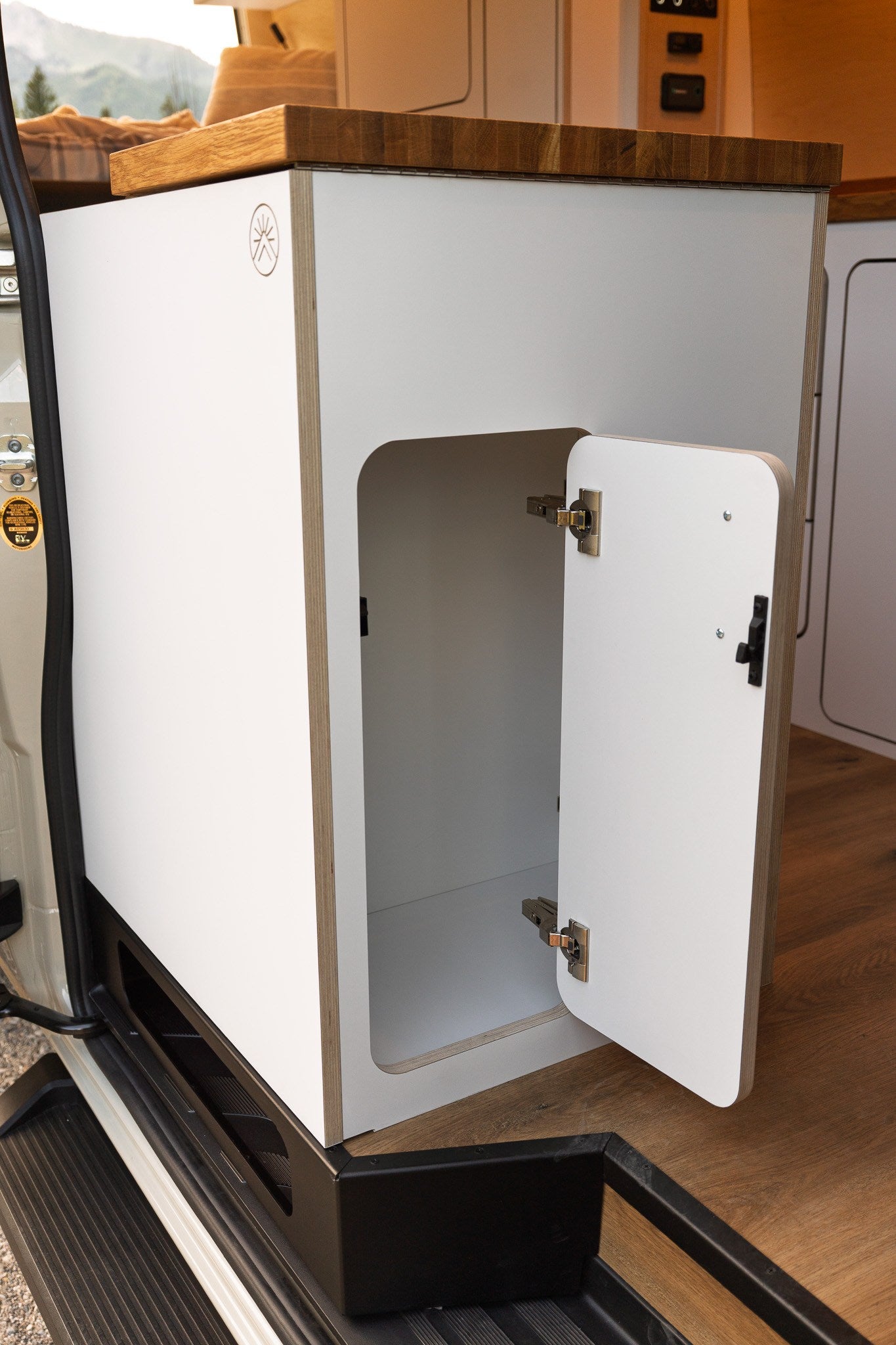 RV rental camper van interior shows open white cabinet, wood counter. Practical storage for travel essentials.