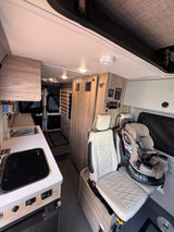 Cozy rv rental interior featuring a kitchenette, child safety seat, and pop-top roof. Ideal for family road trips.