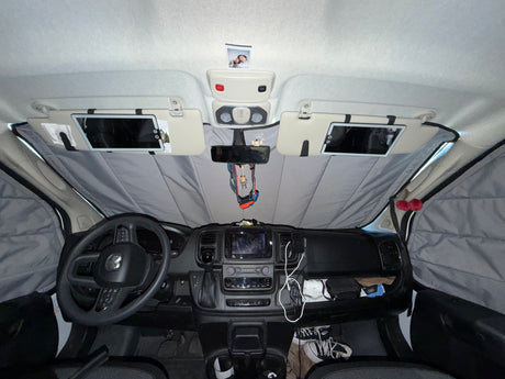 Front cabin of an RV rental, showcasing the dashboard, steering wheel, and full window sunshades for privacy and comfort.
