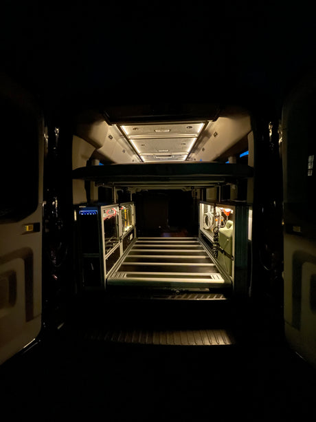 Get a clear view of this rv rental's clever interior design, showcasing smart storage, overhead lighting, and a raised bed.