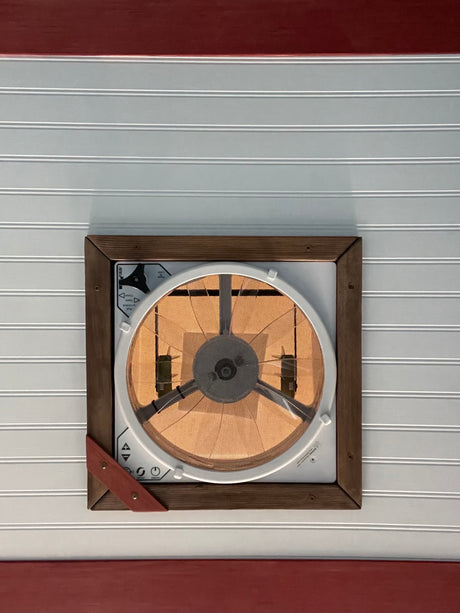 RV rental interior: ceiling fan/vent with a mesh screen, framed by wood, set in white beadboard with red trim.