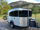 Scenic rv rental setup: A silver travel trailer with bikes parked before a majestic mountain, perfect for outdoor adventures.