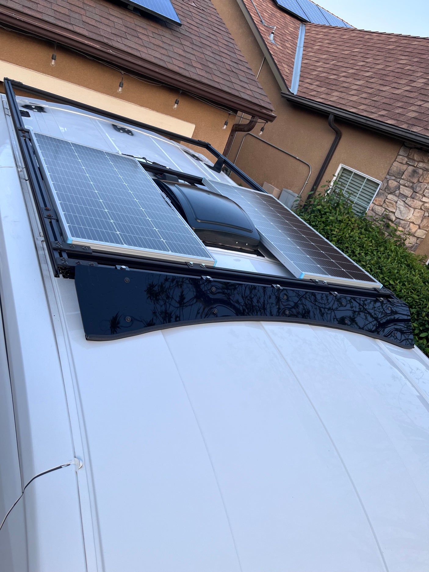 White RV rental roof: two solar panels, central vent fan on a black rack. Ready for off-grid adventures.