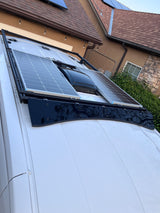 White RV rental roof: two solar panels, central vent fan on a black rack. Ready for off-grid adventures.