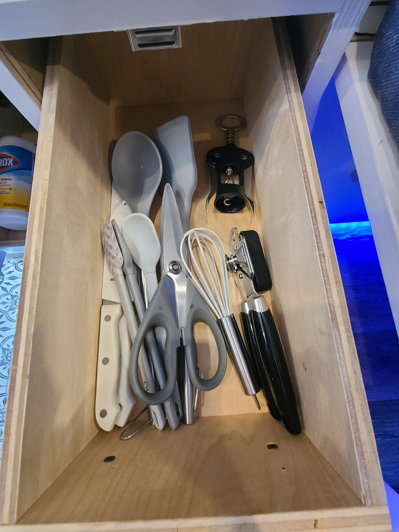 RV rental kitchen drawer stocked with compact essentials: corkscrew, can opener, whisk, spatulas, and knives. — photo 15