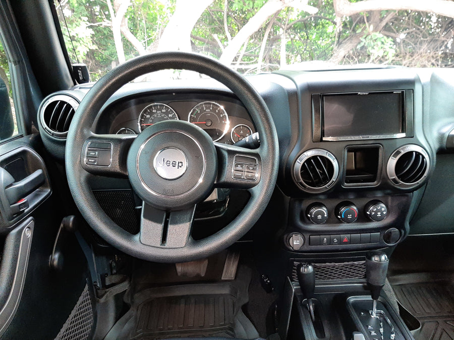Interior of a Jeep Wrangler: dashboard, steering wheel, auto shifter. Ready for rugged trips, like those paired with an rv rental.