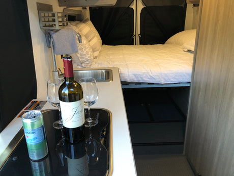 Ready for adventure! This RV rental offers a cozy bed, compact kitchen, wine, and sparkling water for a relaxing trip.