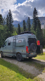This Winnebago Revel 4x4 RV rental is poised for adventure, surrounded by majestic mountains & tall pines.