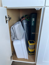 Inside an RV rental cabinet: Essential camping gear, including a propane stove, tarp, and lantern.