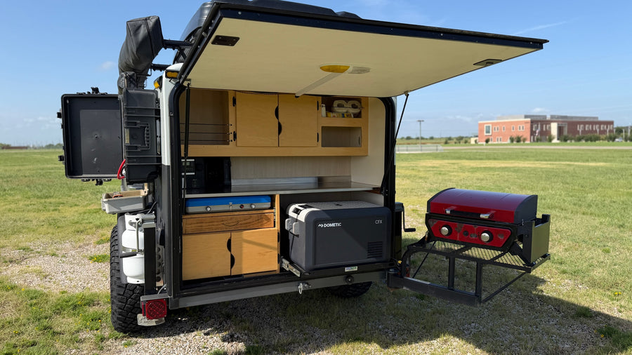 RV rental off-road trailer with open rear kitchen. Features include a Dometic fridge, stovetop, and attached grill.