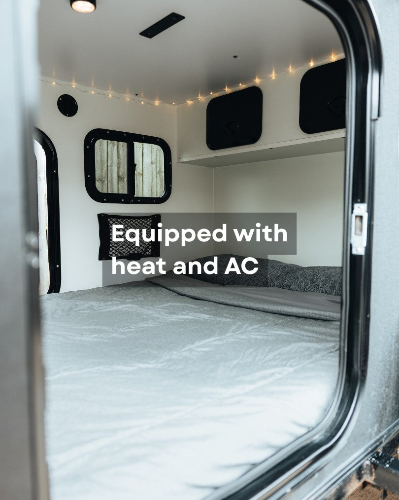 RV rental interior features a comfy bed, window, storage, heat, and AC for your travels.