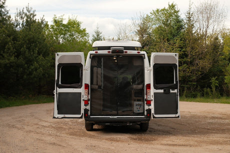 Rear view of a white RV rental camper van with its back doors wide open, revealing a mesh screen interior.