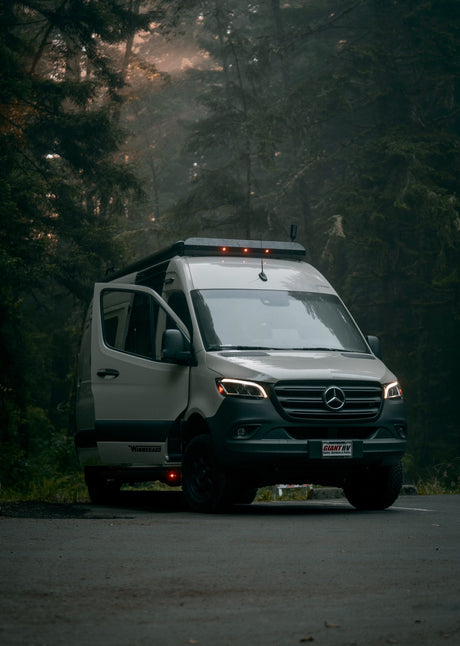 Misty forest RV rental: a white Mercedes camper van, door open, perfect for an off-grid nature adventure.