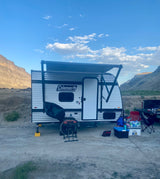 RV rental adventure: Coleman travel trailer set up in a scenic desert canyon, ready for outdoor fun.
