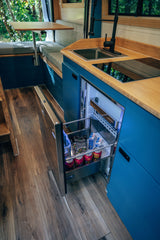 RV rental: functional kitchen with blue cabinets, bamboo counters, sink, cooktop, and a stocked fridge drawer. Dining area too.