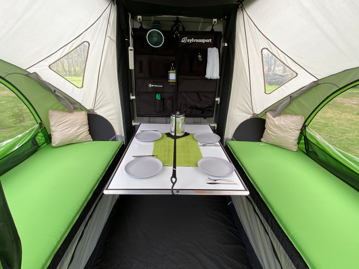 Explore this cozy RV rental interior. It features a dining table, comfortable green beds, and organized storage for your next camping trip. — photo 4