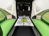 Explore this cozy RV rental interior. It features a dining table, comfortable green beds, and organized storage for your next camping trip.