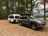 This Lexus SUV with roof cargo box tows a white Little Guy teardrop RV rental, ready for forest camping by the lake.