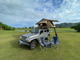 RV rental option: A silver Jeep with a rooftop tent, two chairs, and a cooler on a scenic green golf course.