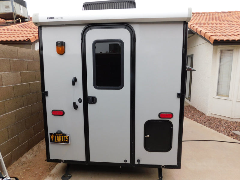 This sleek, compact gray RV rental, equipped with a Thule roof system and ready for travel, features a main door and storage hatch. — photo 3