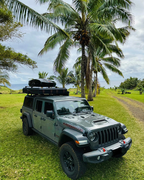 Ready for adventure: Gray Jeep Gladiator Mojave with rooftop tent, a perfect rv rental for tropical camping by the ocean.