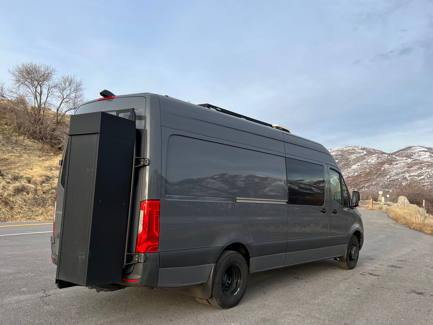 Dark gray adventure van, like an rv rental, with rear storage & roof rack. Parked by snowy mountains, ready for road trips. — photo 8