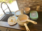 RV rental kitchen with stacked cream dishes, pots with detachable handles, and food storage, ready for cooking and meals.