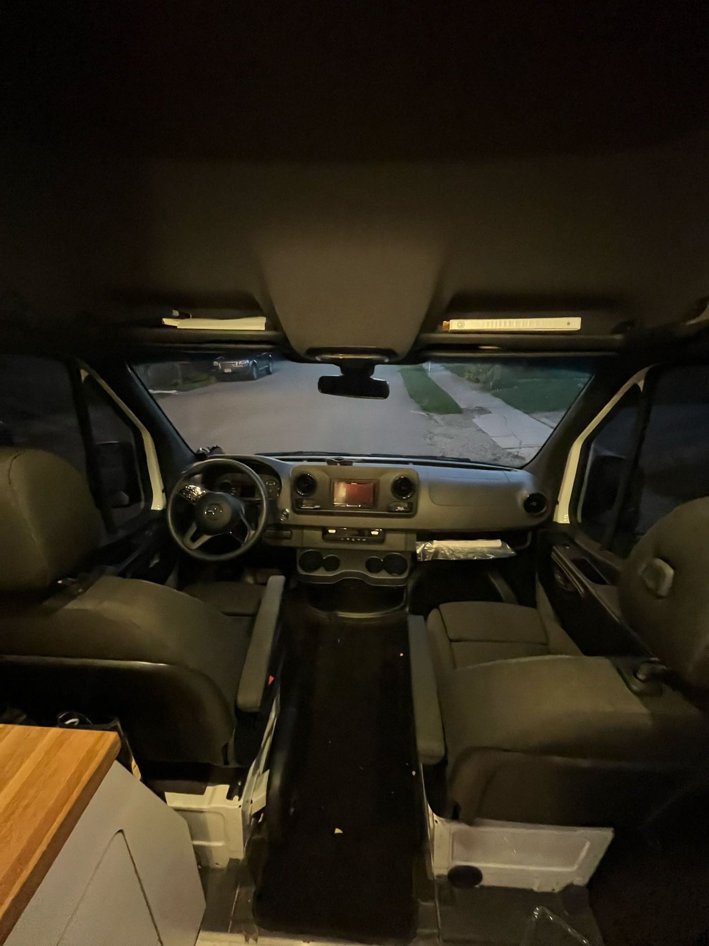 Interior view of an RV rental camper van, from the rear looking forward at the steering wheel, dashboard, and front seats.