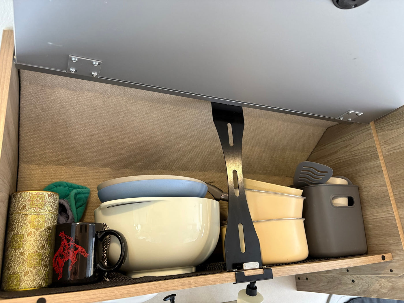 Inside an RV rental: a neat kitchen cabinet with bowls, mugs, utensils, and containers for organized travel. — photo 9