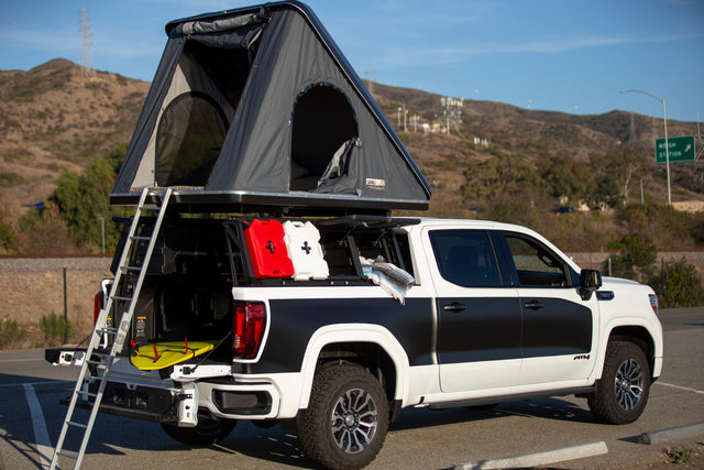 Explore with this RV rental! A GMC AT4 pickup features a rooftop tent, ladder, and gear for your next overlanding adventure.