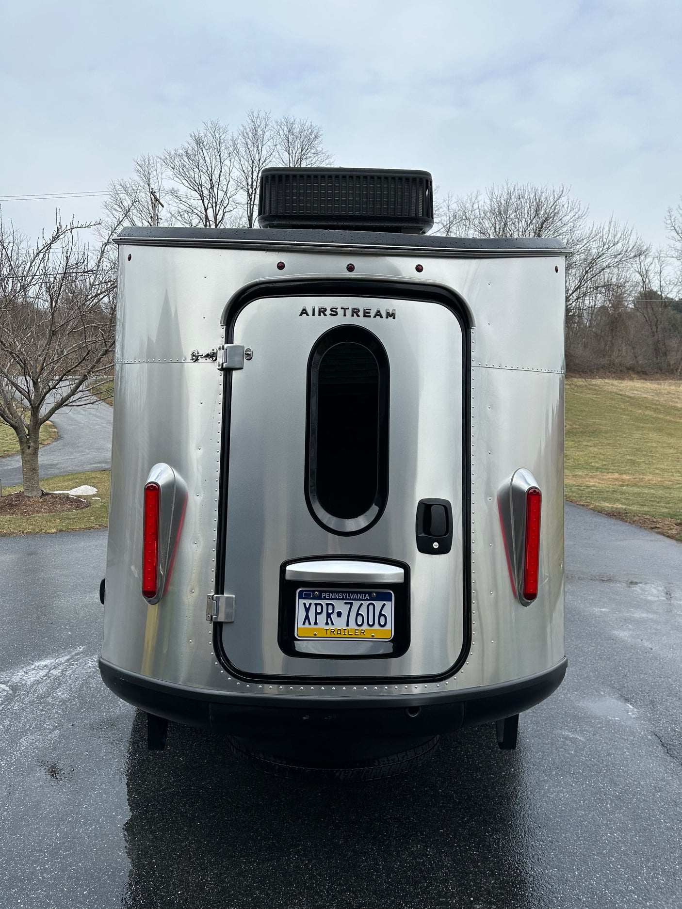 Back of a shiny silver Airstream travel trailer, an excellent RV rental for camping adventures. PA license plate visible.